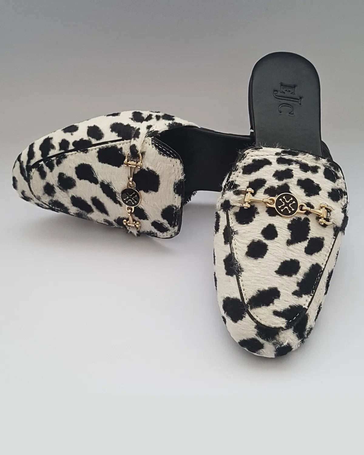 Leopard print slippers with gold chain detail on a gray background