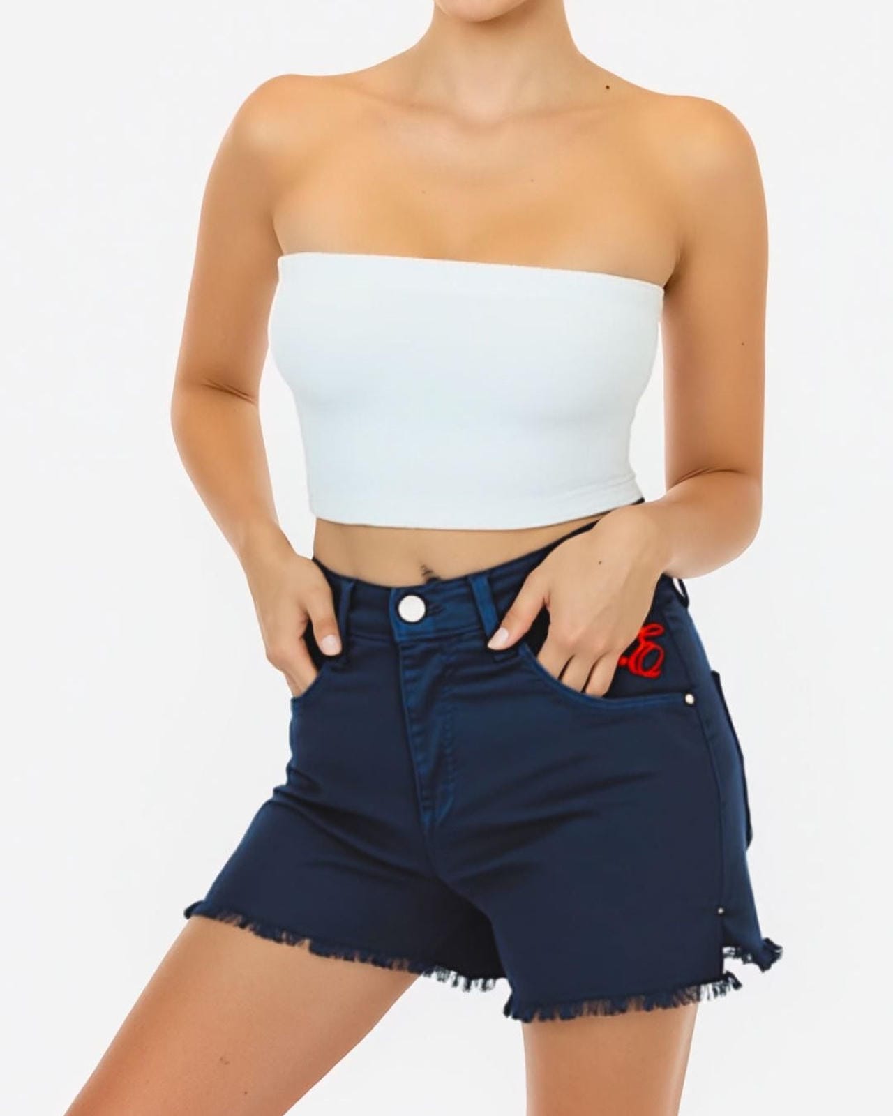 Woman wearing a white strapless top and dark denim shorts on a plain background
