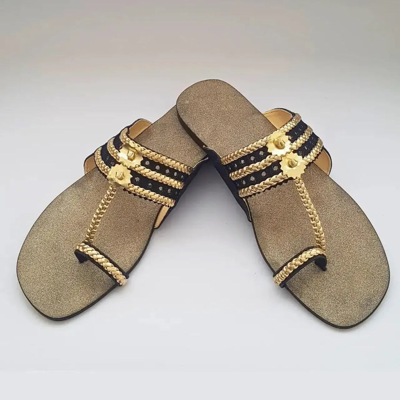 Pair of decorative sandals with gold and black accents on a white background