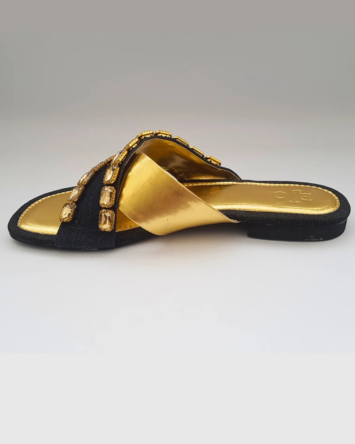 Black sandal with gold accents on a white background