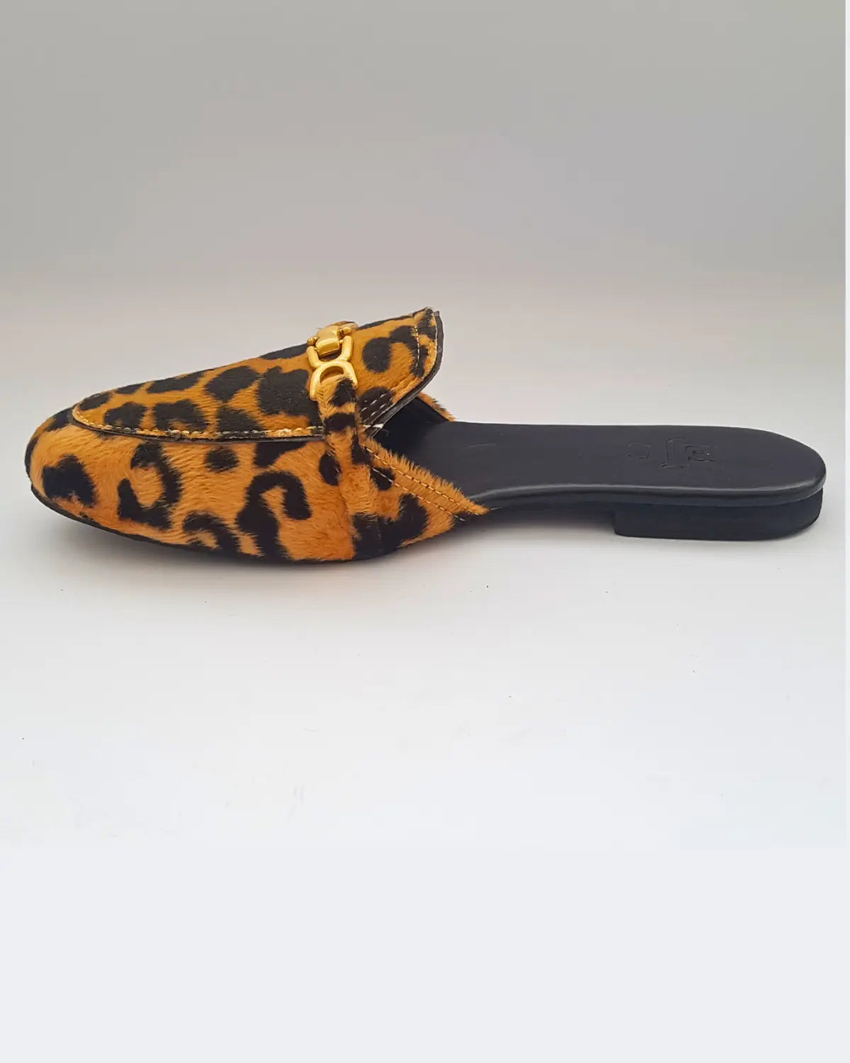 Leopard print slipper with a gold buckle on a white background