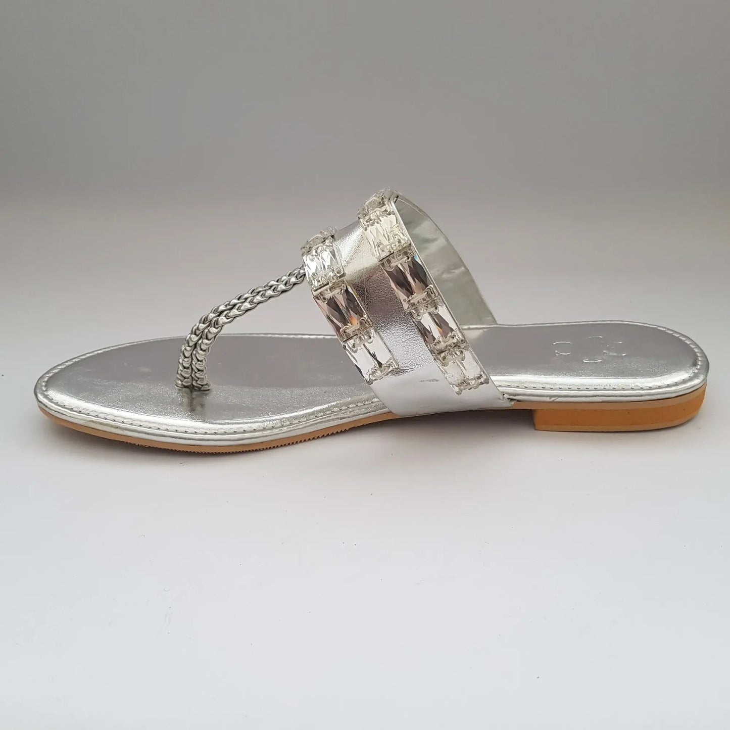 Silver sandal with chain detail on a gray background