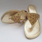 Gold sandal with embellishments on a gray background