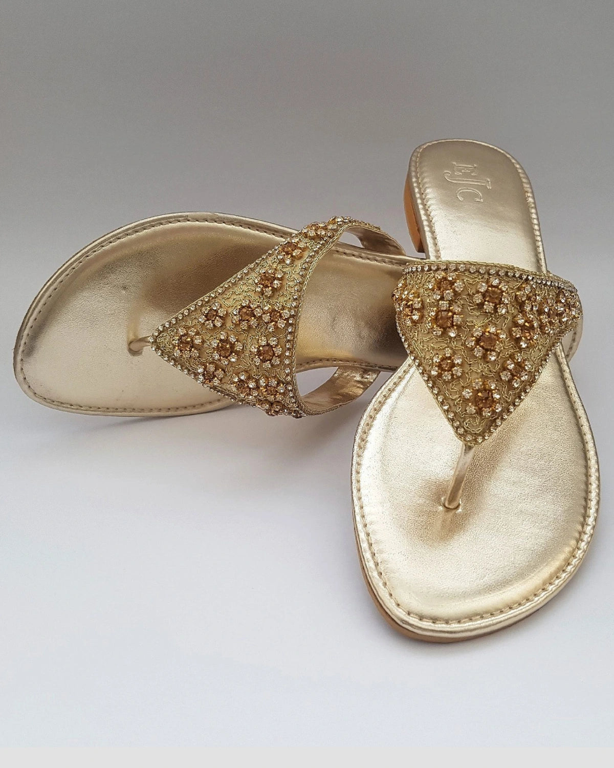 Gold sandal with embellishments on a gray background