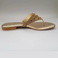 Gold sandal with embellishments on a light gray background