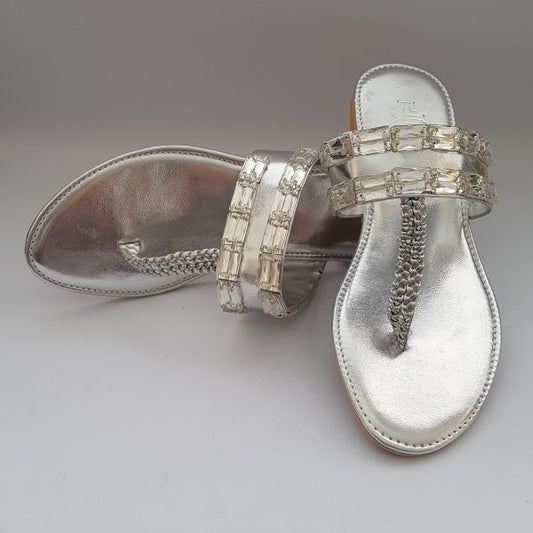 Silver sandal with gemstone straps on a gray background