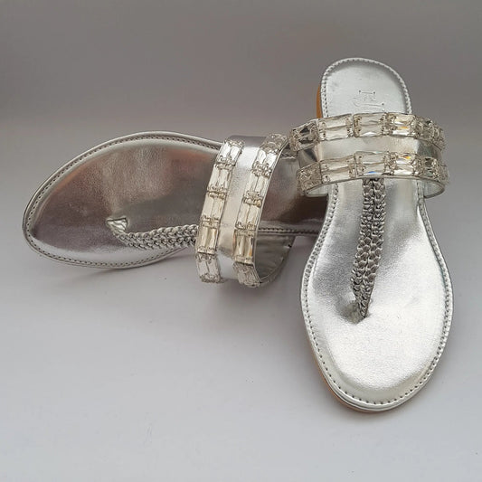 Silver sandal with embellishments on a light gray background