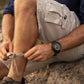 Person tying shoelaces on hiking boots in a natural setting