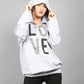 Person wearing a white hoodie with text and black pants on a gray background