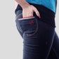 Person wearing blue jeans with red stitching on a plain background