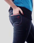 Person wearing blue jeans with red stitching on a plain background