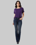 Woman wearing a purple shirt and dark blue jeans on a light gray background
