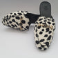 Leopard print slippers with gold chain detail on a gray background