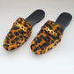 Pair of leopard print slippers with gold accents on a white background