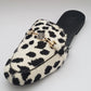 White slipper with black spots and gold logo on a white background