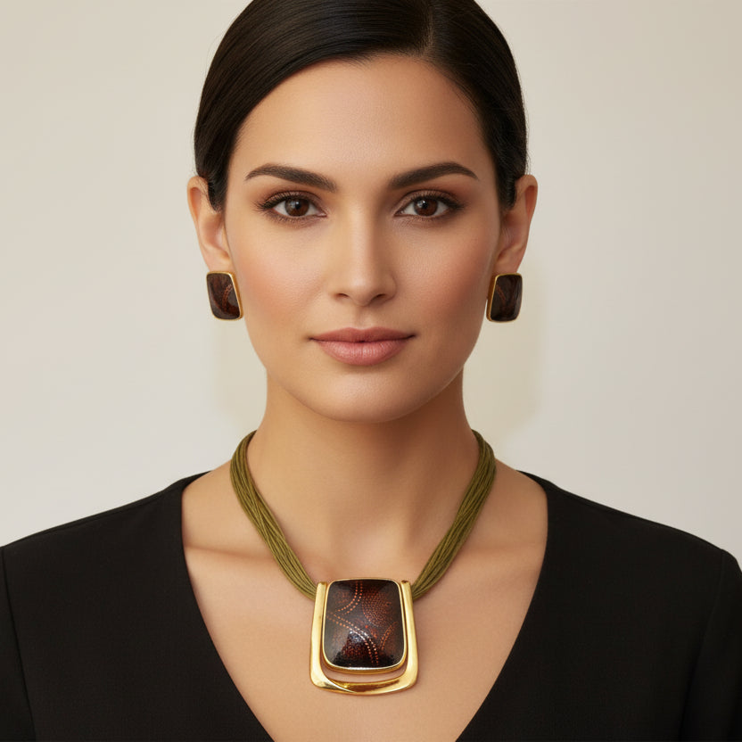 Gold necklace with a dark brown pendant on a black mannequin bust against a white background