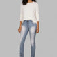 Woman wearing a white sweater and light blue jeans on a gray background