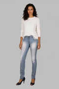 Woman wearing a white sweater and light blue jeans on a gray background