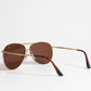 Sunglasses with gold frame and brown lenses on a white background