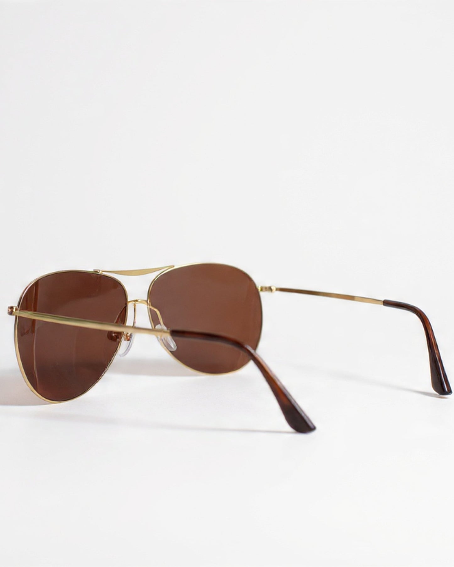 Sunglasses with gold frame and brown lenses on a white background