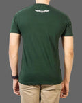 Person wearing a green t-shirt with a logo on the back against a gray background