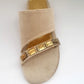 Beige sandal with gold embellishments on a white background