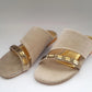 Beige sandals with gold straps on a white background