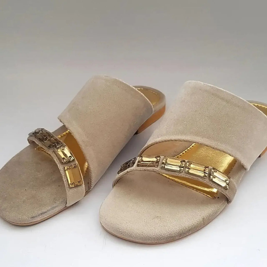 Beige sandals with gold straps on a white background