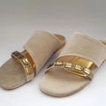 Beige sandals with gold straps on a white background