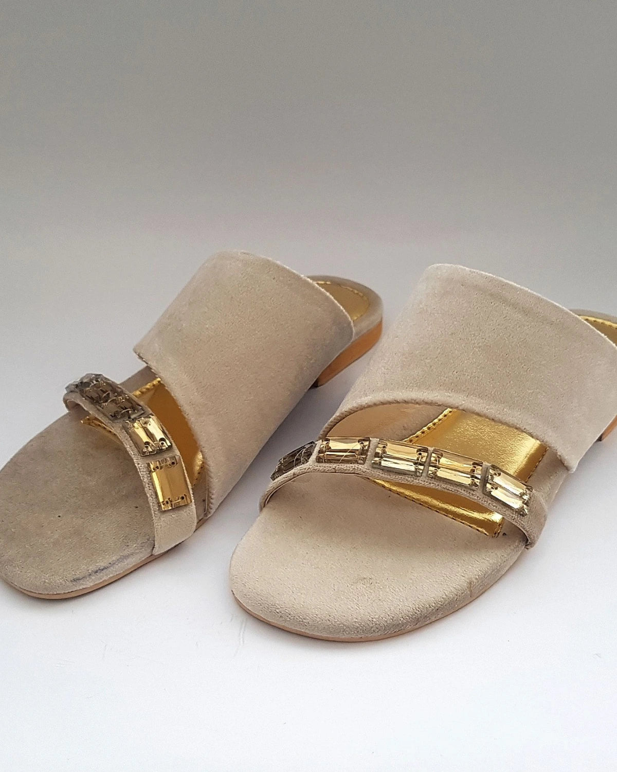 Beige sandals with gold straps on a white background
