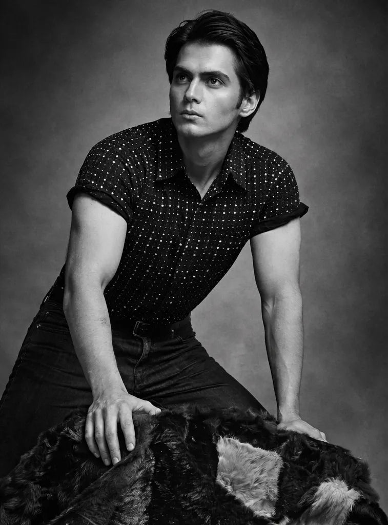 Black and white portrait of a man wearing a patterned shirt and watch.