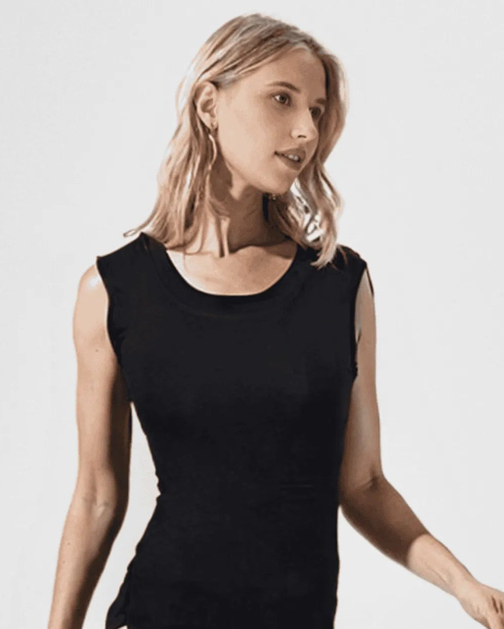 Woman wearing a black sleeveless bodysuit against a white background