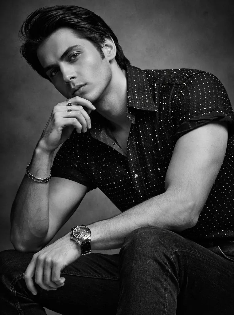 Black and white portrait of a man wearing a patterned shirt and watch.