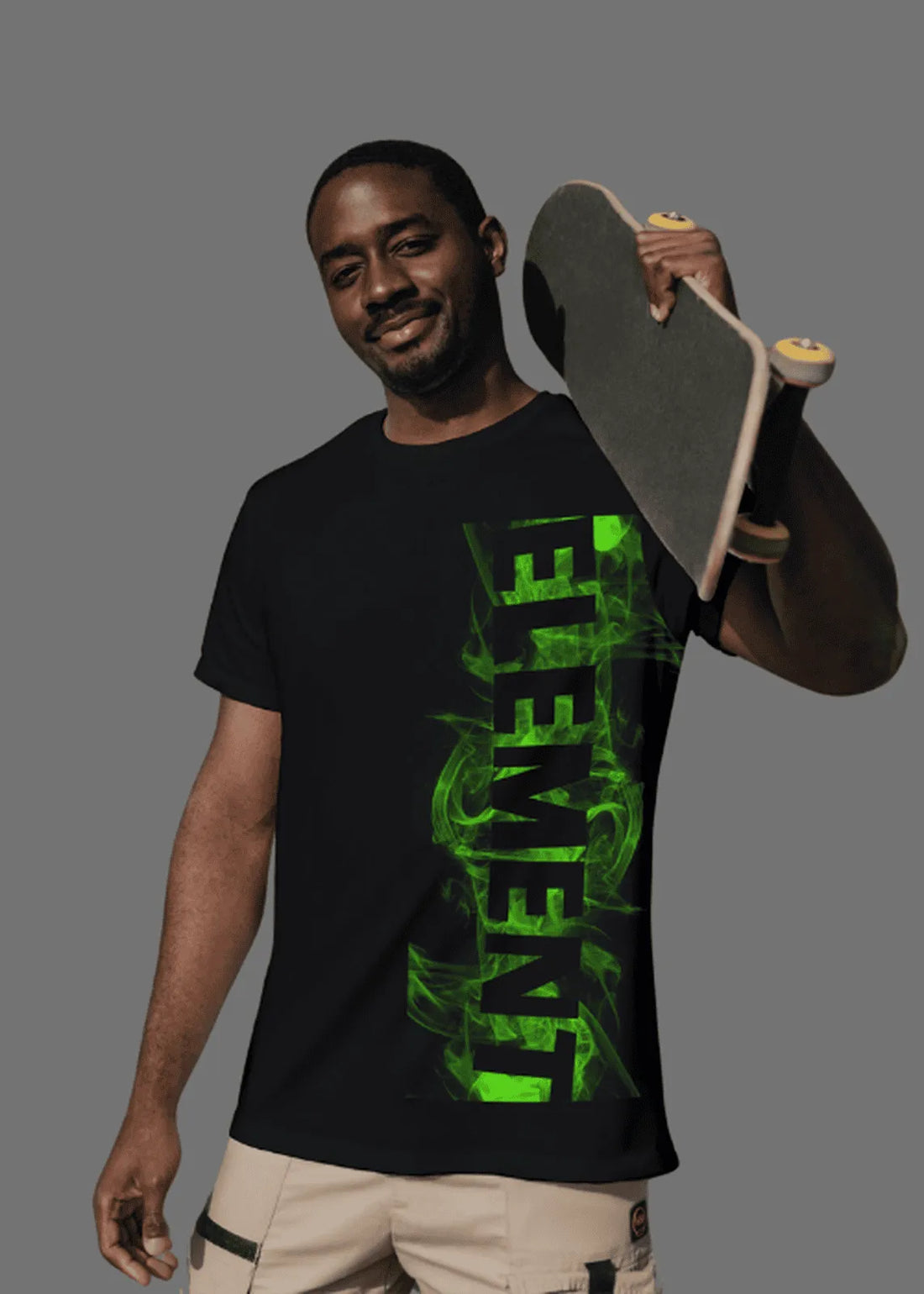 Man wearing a black t-shirt with green text holding a skateboard against a gray background