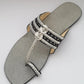 Silver sandal with braided straps on a gray background