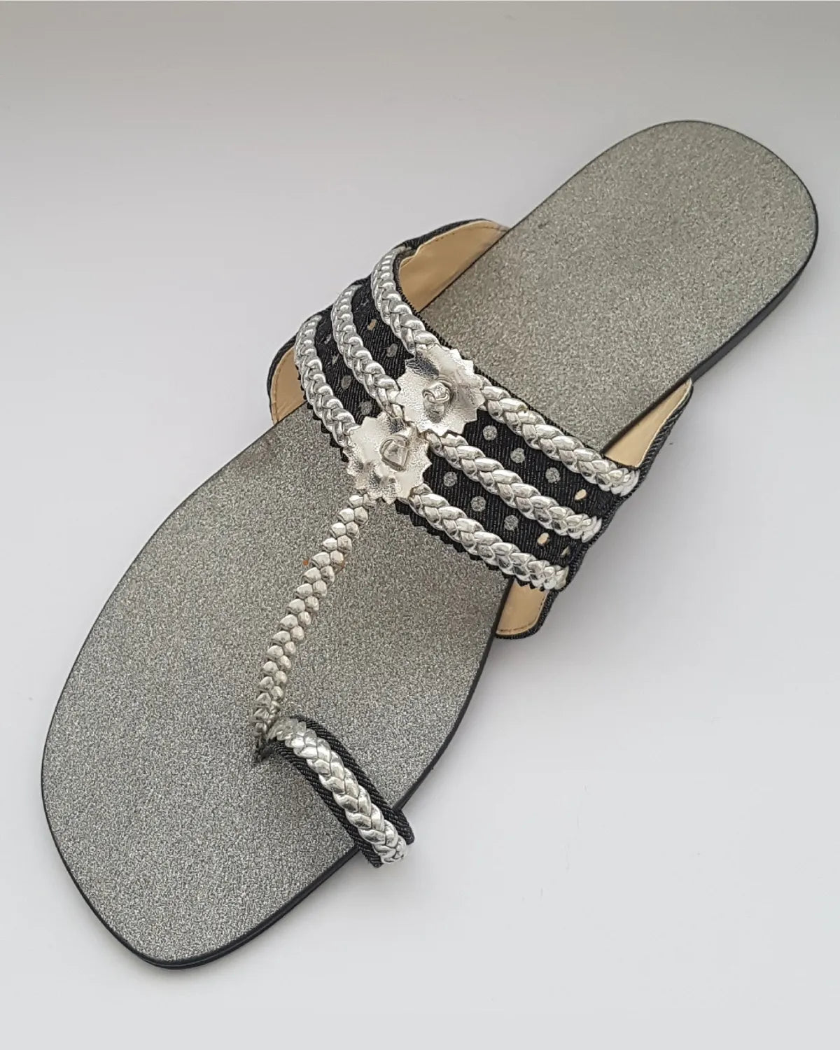 Silver sandal with braided straps on a gray background