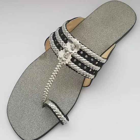 Silver sandal with braided straps on a gray background