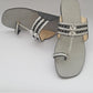 Pair of gray sandals with decorative straps on a light gray background