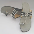 Pair of gray sandals with decorative straps on a light gray background