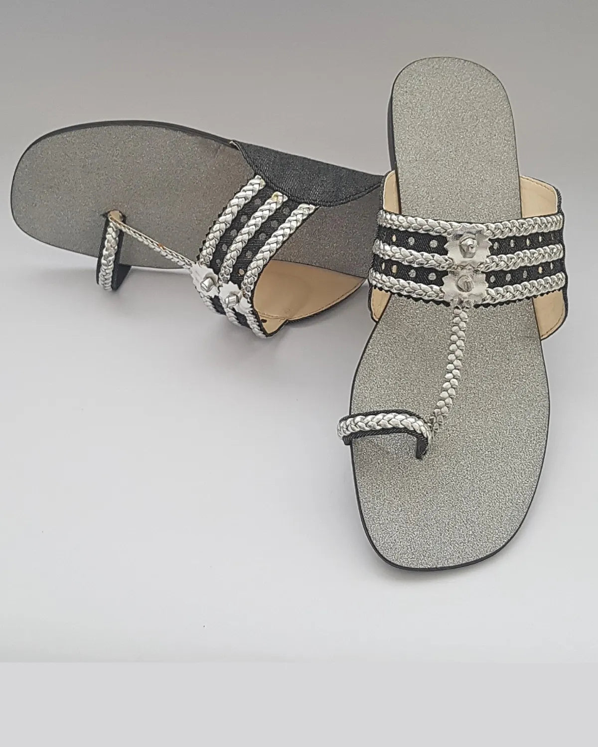 Pair of gray sandals with decorative straps on a light gray background