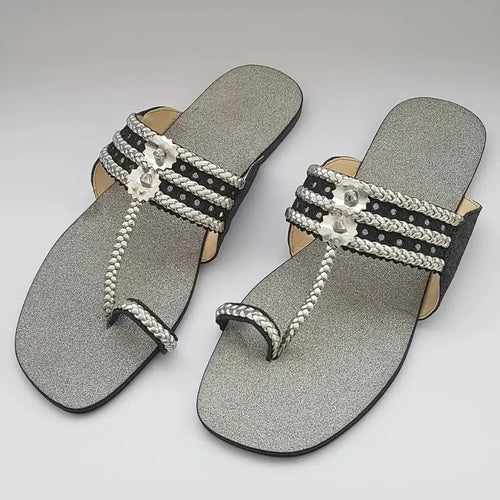Pair of silver sandals with decorative straps on a light gray background