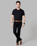 Man wearing a black t-shirt, black pants, and brown shoes on a gray background