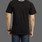 Person wearing a black t-shirt with a logo on the back against a gray background