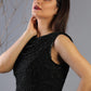 Woman wearing a black beaded top against a gray background