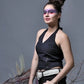 Woman wearing a black top and pants with decorative elements, standing against a gray background.