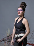 Woman wearing a black top and pants with decorative elements, standing against a gray background.