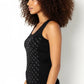 Woman wearing a black tank top with white patterns against a plain background