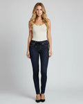 Woman wearing dark blue jeans and a white top on a gray background
