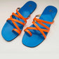 Blue sandals with orange straps on a light gray background