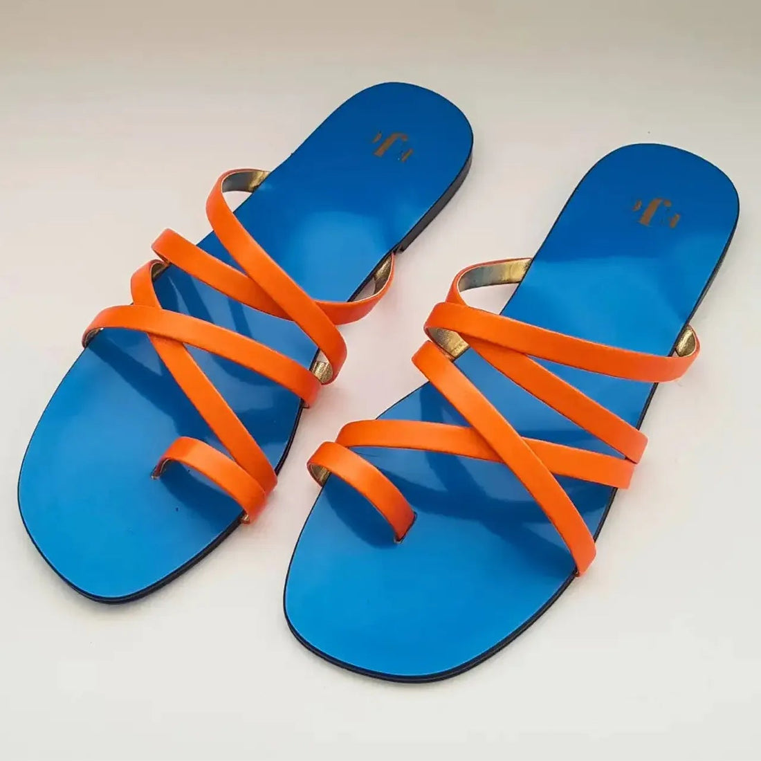 Blue sandals with orange straps on a light gray background